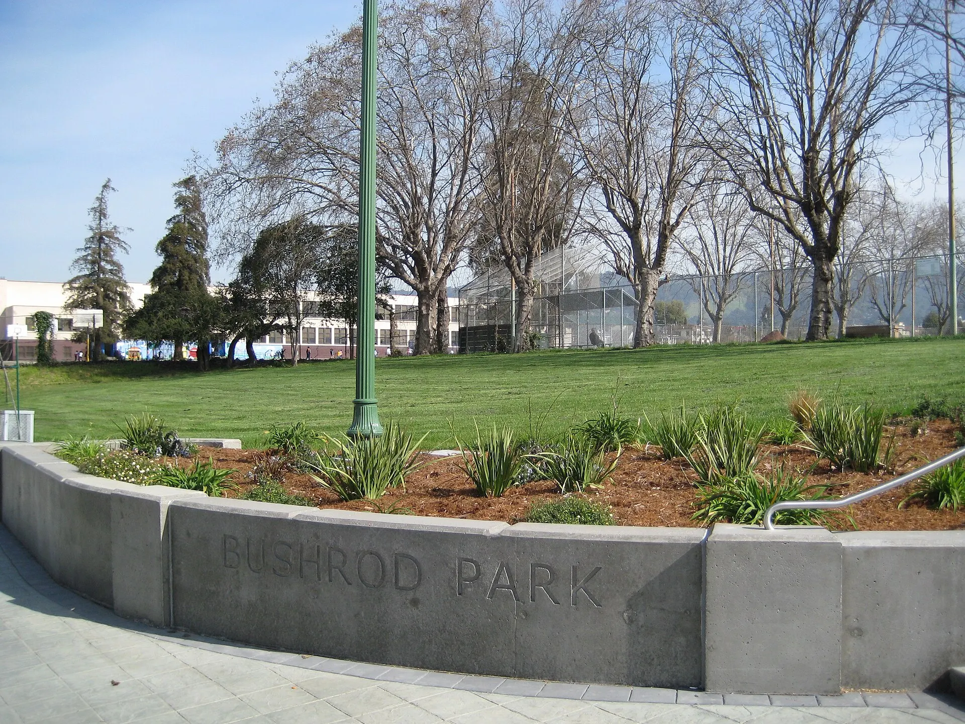 The concrete Bushrod Park sign in front of a lawn and bare winter trees
