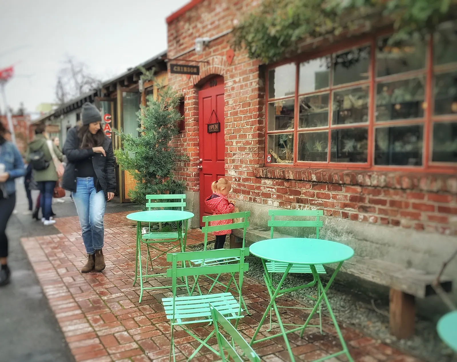 A brick storefront with green café tables in Temescal Alley